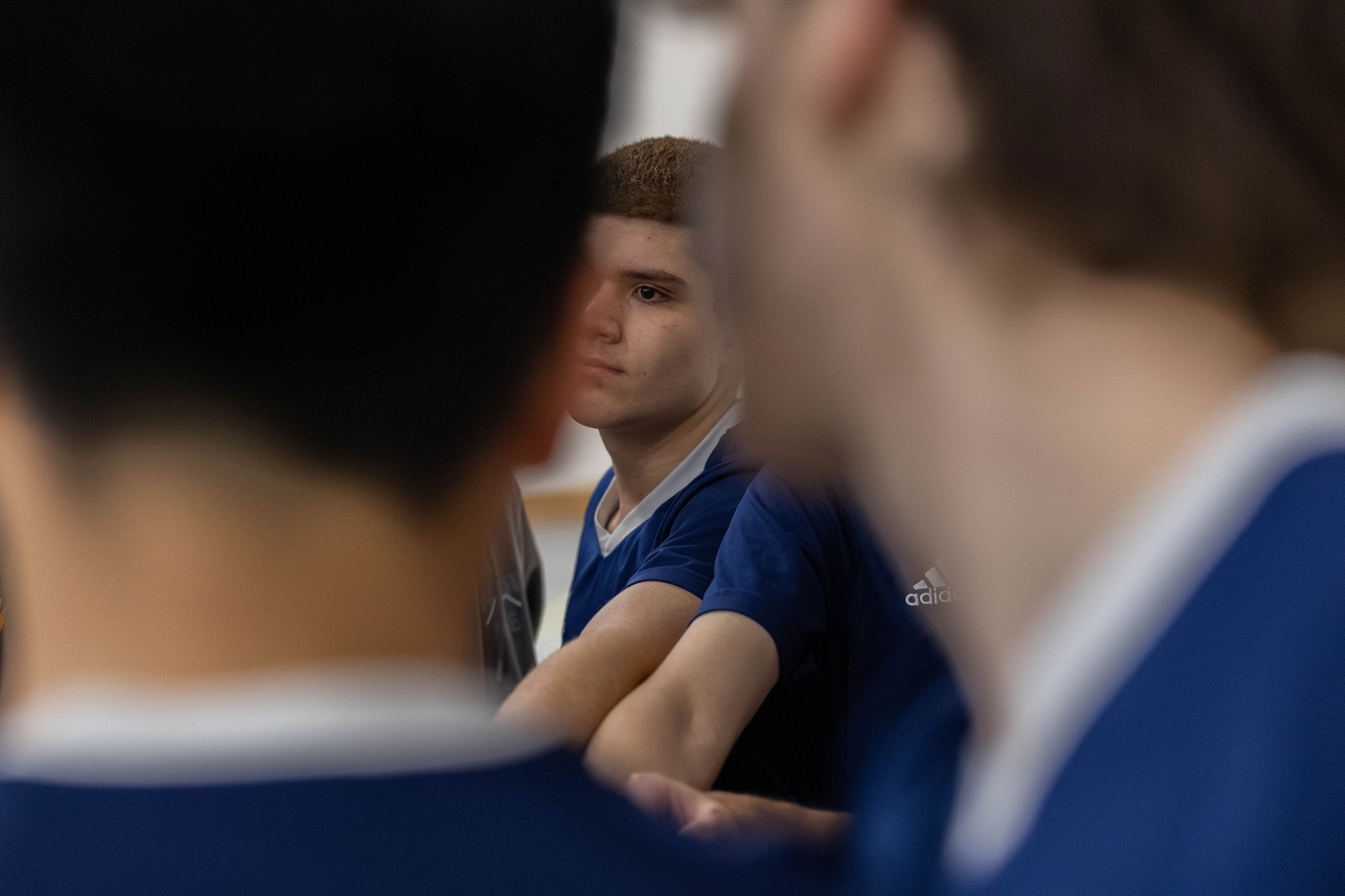 Focused basketball player framed between teammates in a timeout huddle