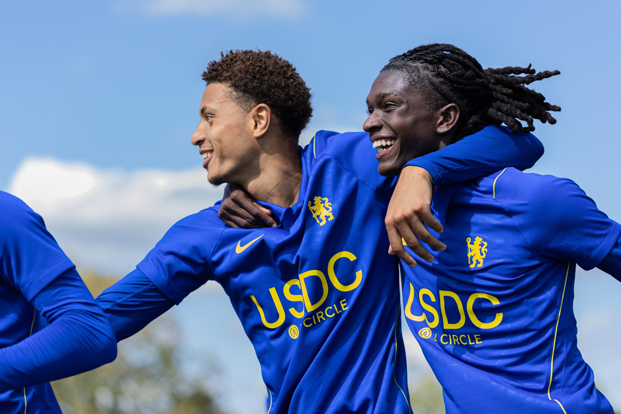 Two Chelsea players laughing arm in arm after a goal